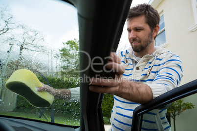 Auto service staff washing a windscreen with sponge