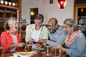 Friends looking their photos on mobile phone in bar
