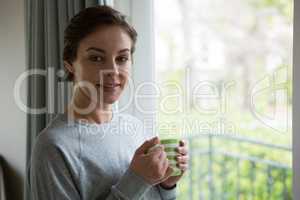 Smiling woman having cup of coffee at home