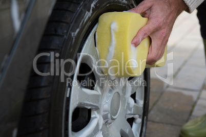 Auto service staff washing a car tyre with sponge