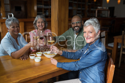 Happy senior friends having glass of wine in bar