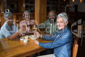 Happy senior friends having glass of wine in bar