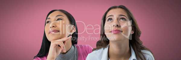 Two women looking up with pink background