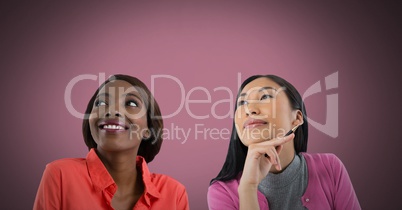 Two women looking up with pink background