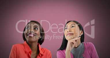 Two women looking up with pink background