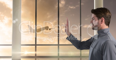 Businessman waving goodbye to plane out window