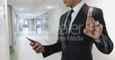 Businessman touching air with phone in front of corridor