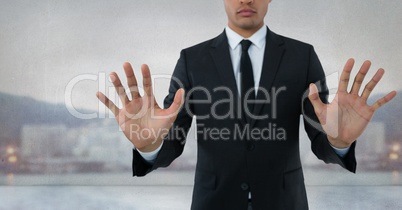 Businessman touching air with open hands in front of city