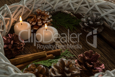 Close up of illuminated candles with pine cones and wreath