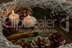 Close up of illuminated candles with pine cones and wreath