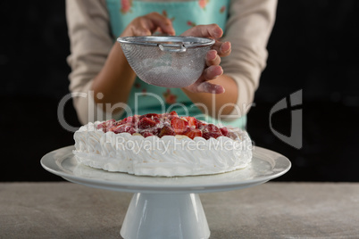 Woman icing sugar on tart