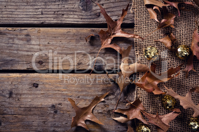 Sequin balls and dry leaves on wooden plank