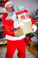 Santa claus holding a stack of gifts at home