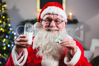 Santa Claus having christmas cookie with a glass of milk