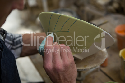 Male potters hand painting a bowl
