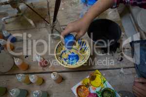 Girl decorating bowl with paint