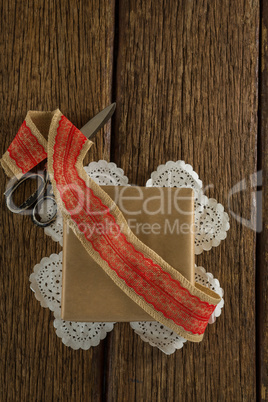 Wrapped gift, ribbon and scissors on wooden plank