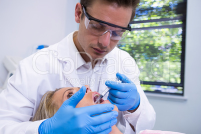 Dentist giving anesthetic to woman at medical clinic