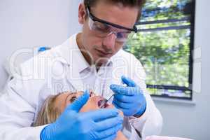 Dentist giving anesthetic to woman at medical clinic