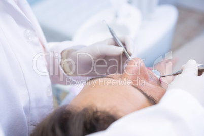 Dentist giving dental treatment to man at clinic