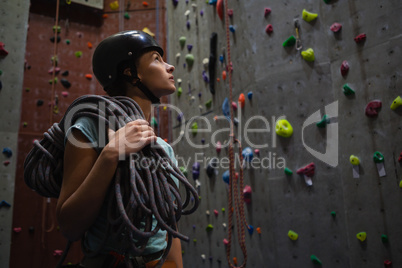 Athlete carrying rope looking up while standing in fitness studio Athlete carrying rope looking up while standing in fitness studio