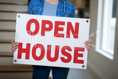 Woman standing in the living room holding open sign