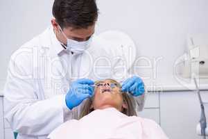 Dentist holding equipment while cleaning woman teeth