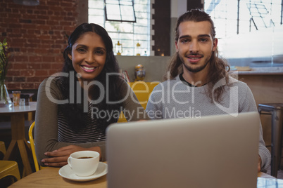 Portrait of young friends with laptop at cafe