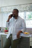 Man talking on mobile phone in kitchen
