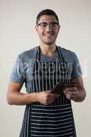 Smiling waiter standing with a digital tablet