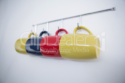 Close-up of colorful mugs hanging on hook