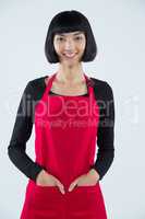 Smiling waitress standing with hands in pocket against white background