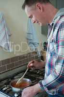 Man stirring food in pan at kitchen