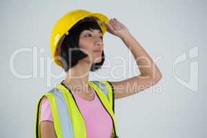 Female architect in hard hat looking away against white background
