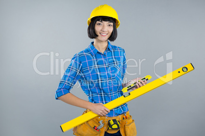 Female architect holding measuring equipment against grey background