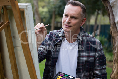 Man painting on canvas in garden