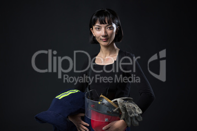 Female architect holding helmet and gloves against black background