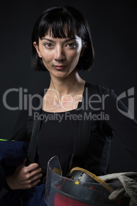 Female architect holding helmet and gloves against black background