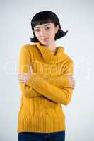 Woman in warm cloths standing with arms crossed against white background
