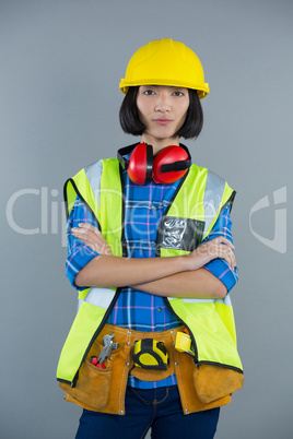 Female architect standing with arms crossed against grey background