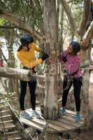 Two female friends enjoying zip line adventure in park