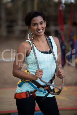 Smiling woman holding harness in park