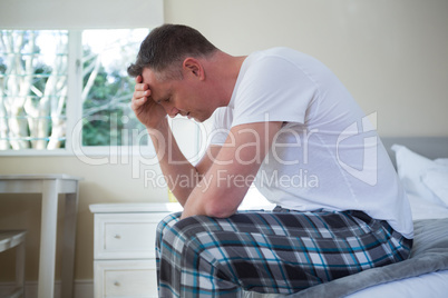 Worried man having a headache in bedroom