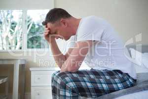 Worried man having a headache in bedroom