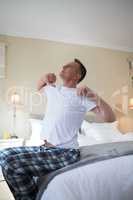 Man waking up in bed and stretching his arms