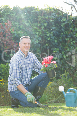 Smiling man holding pot plant in garden