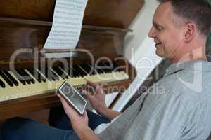 Man using digital tablet while playing piano