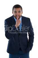 Businessman standing with finger on lips