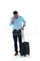 Male executive with luggage talking on mobile phone