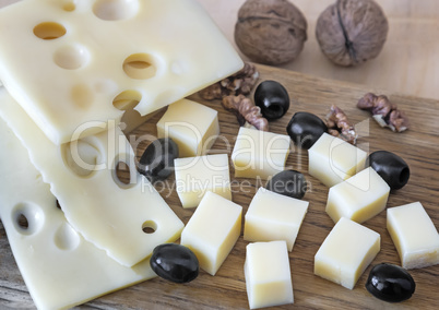 Cheese , nuts and olives on the table.